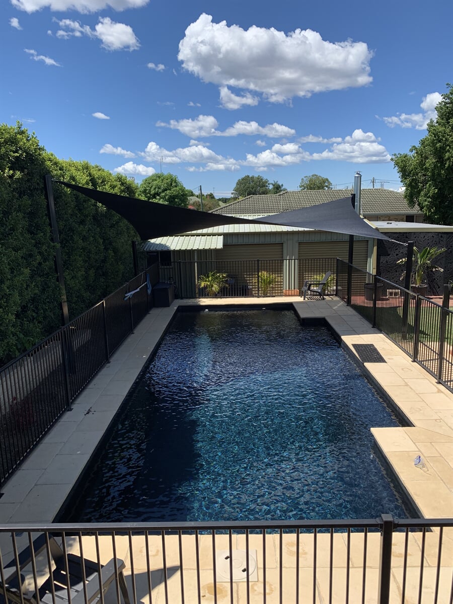 Waterproof black shade sails installed over a backyard swimming pool in Grafton on the North Coast